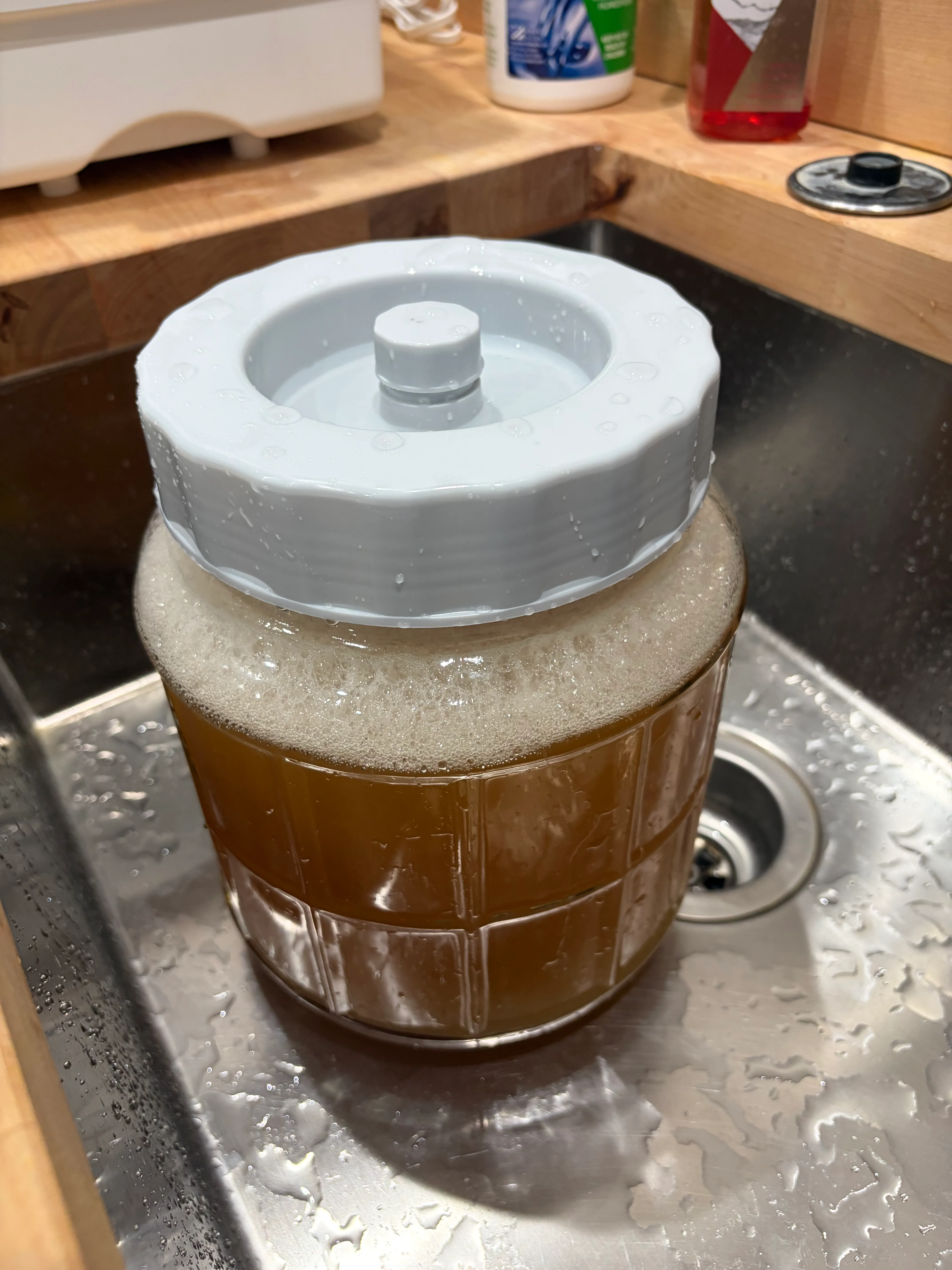 A few hours in — a real foam cap, and the jar living in the sink just in case