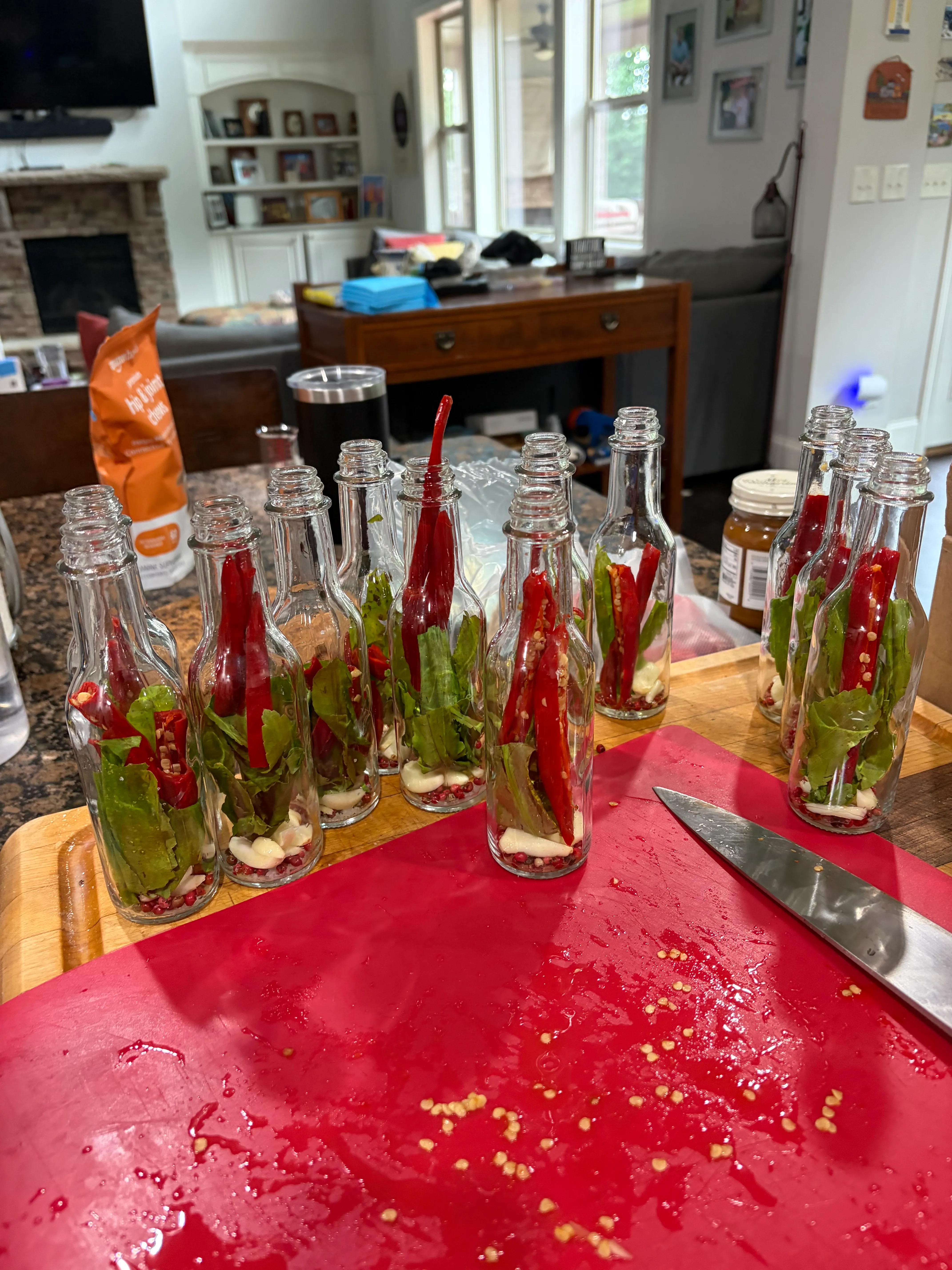 Bottles packed with whole red chilis and green culantro leaves, ready for vinegar