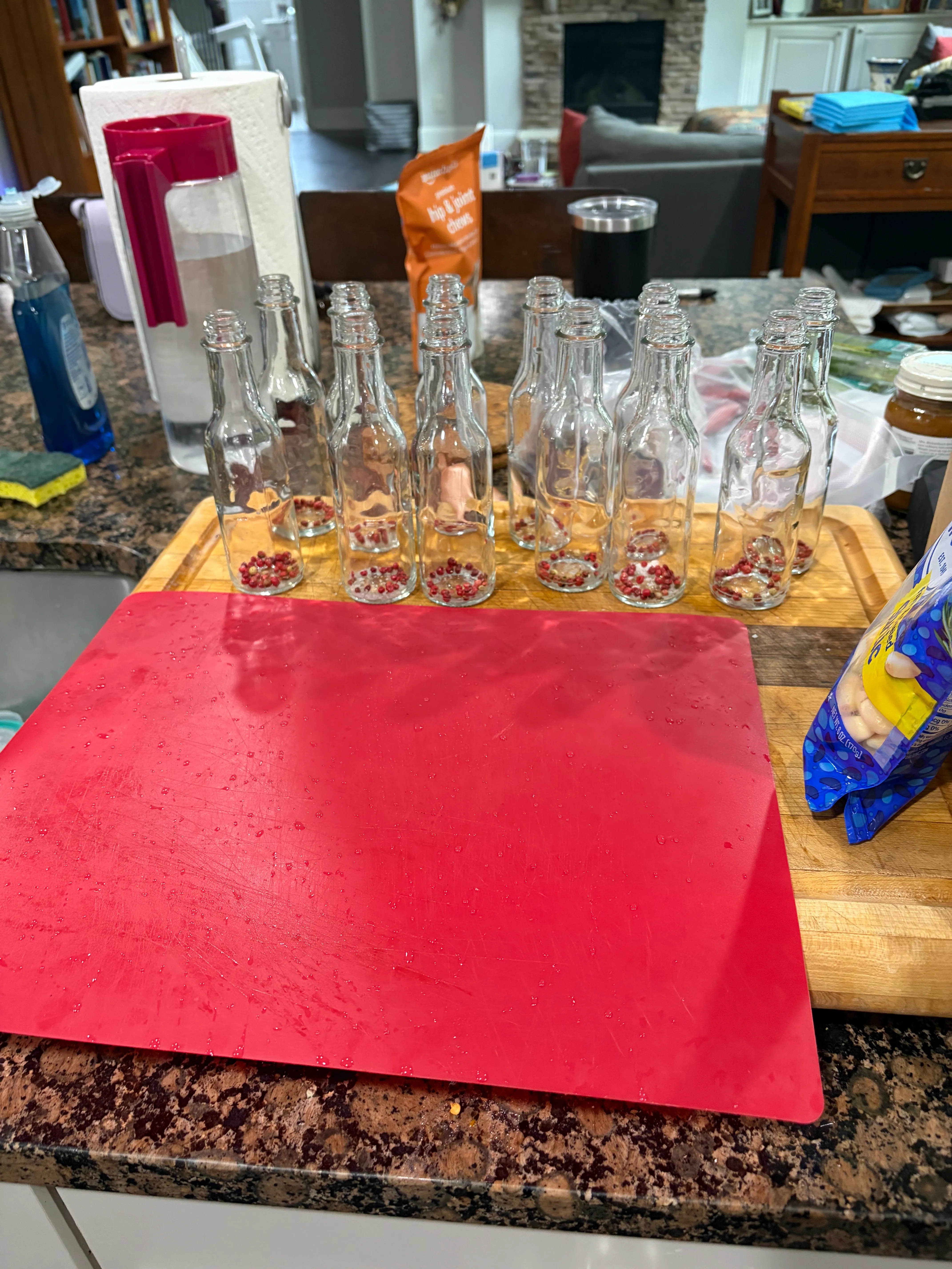 The first layers going in — pink peppercorns and rough-cut garlic in the bottoms of the bottles